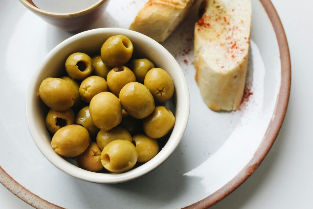 A delicious serving of green olives and sliced bread, perfect for a light snack.