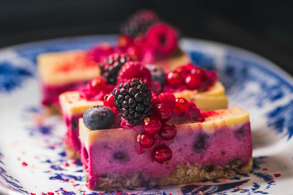 Sliced berry cheesecake topped with vibrant fresh berries and served on a decorative plate.
